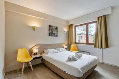 a bedroom with a bed and two yellow chairs at Sleep & Go Brussels South in Waterloo