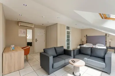 a living room with a couch and a bed at Sleep & Go Brussels South in Waterloo