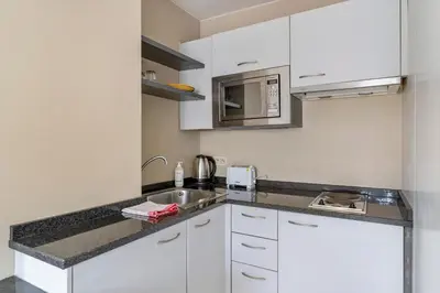 a kitchen with white cabinets and a sink at Sleep & Go Brussels South in Waterloo