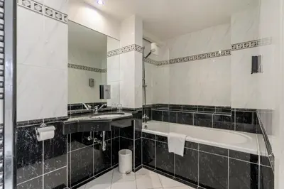 a bathroom with a tub and a sink and a mirror at Sleep & Go Brussels South in Waterloo