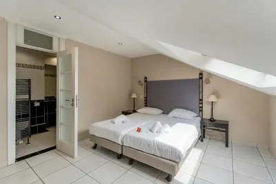 a bedroom with a large white bed and a bathroom at Sleep & Go Brussels South in Waterloo