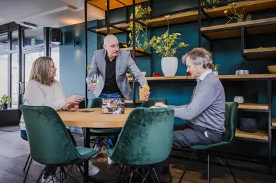 three people sitting around a table with wine glasses at Corbie Mol in Mol