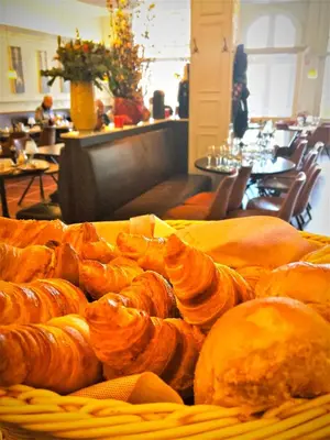 a basket of pastries on a table in a restaurant at Hotel Mille Colonnes in Leuven