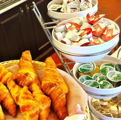 a table with a basket of pastries and bowls of food at Hotel Mille Colonnes in Leuven
