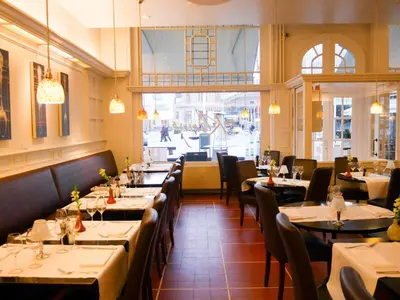 a restaurant with tables and chairs and a large window at Hotel Mille Colonnes in Leuven