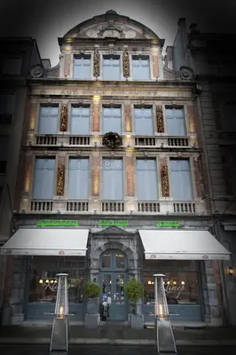 a large brick building with a store front at Hotel Mille Colonnes in Leuven