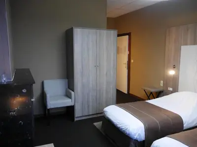 a bedroom with a bed and a cabinet and a chair at Hotel Mille Colonnes in Leuven
