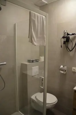 a shower stall with a toilet in a bathroom at Hotel Mille Colonnes in Leuven