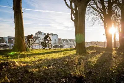two people riding bikes in a park with trees at Turnhout City Hotel in Turnhout
