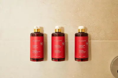 three red shampoo bottles on a tile wall at Hotel FRANQ in Antwerp