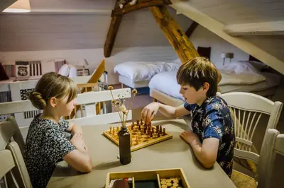 two children playing chess at a table in a room at B&B Hullebrug in Heist-op-den-Berg