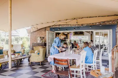 a woman standing at a table in a restaurant at B&B Hullebrug in Heist-op-den-Berg