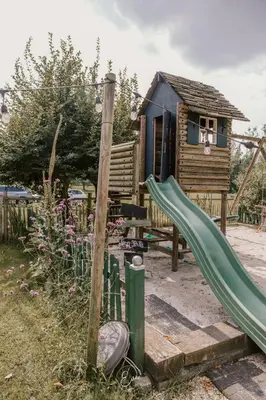 a playground with a slide and a wooden house at B&B Hullebrug in Heist-op-den-Berg