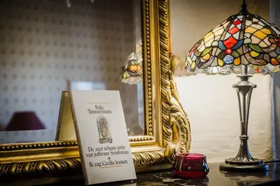 a sign on a table with a lamp and a mirror at B&B Hullebrug in Heist-op-den-Berg