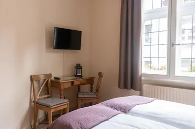 a bedroom with a desk and a bed and a tv at Hotel La Vieille Lanterne in Brussels