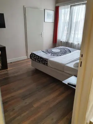 a bedroom with a bed and a wooden floor at Hotel Queen Mary in Brussels