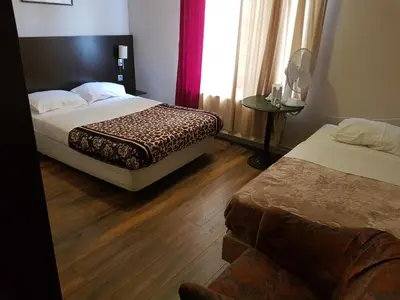 a hotel room with two beds and a couch at Hotel Queen Mary in Brussels