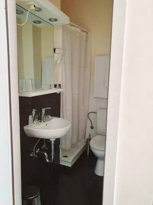 a bathroom with a sink and a toilet and a mirror at Hotel Queen Mary in Brussels