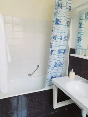 a bathroom with a shower curtain and a sink at Hotel Queen Mary in Brussels