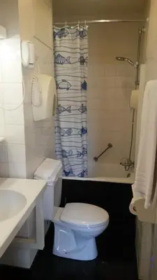 a bathroom with a toilet and a sink and a tub at Hotel Queen Mary in Brussels
