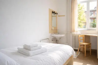 a white bedroom with a sink and a bed with towels at Institute Of Cultural Affairs in Brussels
