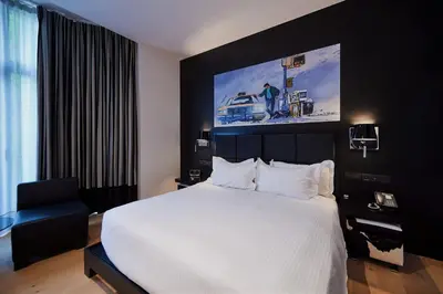 a bedroom with a large white bed and a black wall at YOOMA Urban Lodge in Brussels