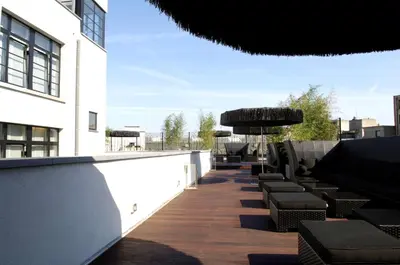 a patio with chairs and an umbrella on a building at YOOMA Urban Lodge in Brussels