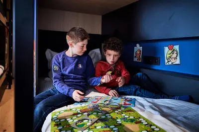 two young boys sitting in a bed playing a board game at YOOMA Urban Lodge in Brussels