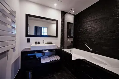 a bathroom with a sink and a tub and a mirror at YOOMA Urban Lodge in Brussels