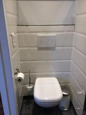 a white bathroom with a toilet and a roll of toilet paper at Le Jardin Des Sources in La Hulpe