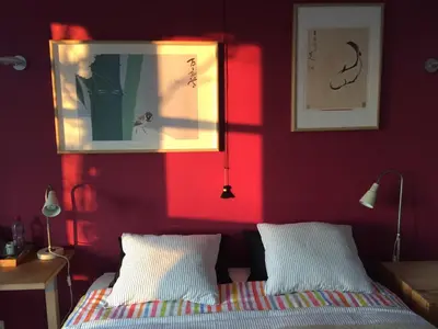 a bedroom with red walls and a bed with white pillows at Le Jardin Des Sources in La Hulpe