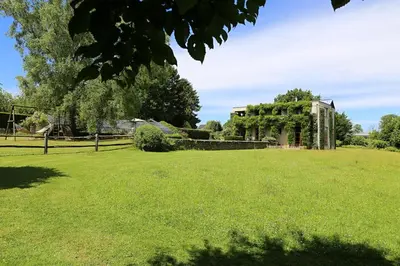 a large grassy field with a house in the background at Le Jardin Des Sources in La Hulpe