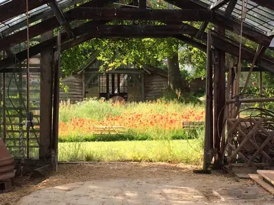 an open barn with a field of flowers at Le Jardin Des Sources in La Hulpe