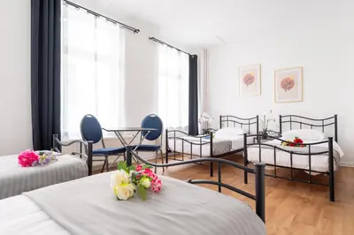 a room with four beds and tables with flowers on them at Hotel Le Grand Colombier in Brussels