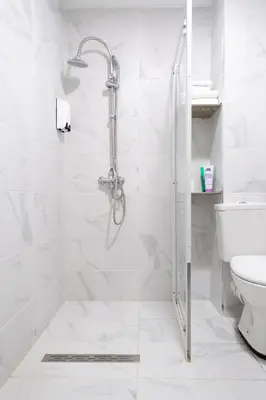 a white bathroom with a shower and a toilet at Hotel Abberdeen in Brussels