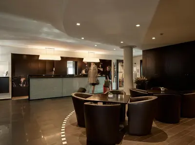 a lobby with tables and chairs and a kitchen at Gosset Hotel in Groot-Bijgaarden