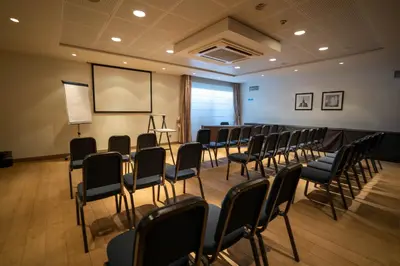 a room with a bunch of chairs and a screen at Gosset Hotel in Groot-Bijgaarden