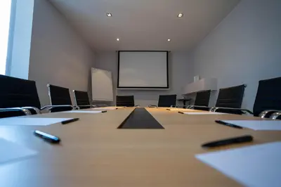 a conference room with a table and chairs and a screen at Gosset Hotel in Groot-Bijgaarden