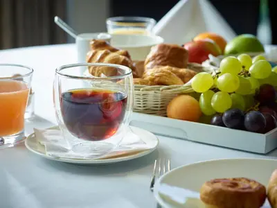 a table with a plate of food and a basket of fruit at Gosset Hotel in Groot-Bijgaarden