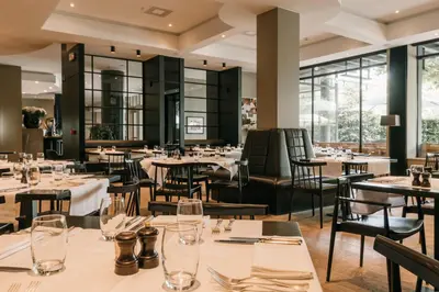 a restaurant with tables and chairs and windows at Serwir Hotel in Sint-Niklaas