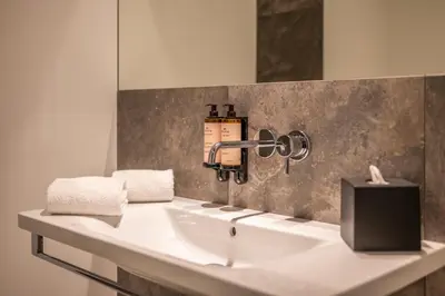 a bathroom sink with a soap dispenser on a wall at Serwir Hotel in Sint-Niklaas