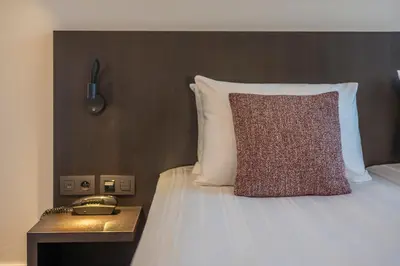 a bed with a pillow and a table with a phone at Serwir Hotel in Sint-Niklaas