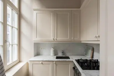 a white kitchen with white cabinets and a sink at Cozy & Bright Apartment in Antwerp