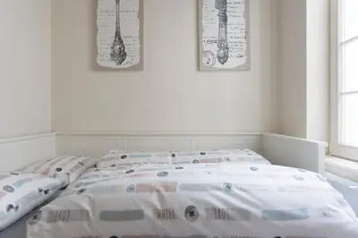 a white bedroom with a bed with pillows on it at Cozy & Bright Apartment in Antwerp