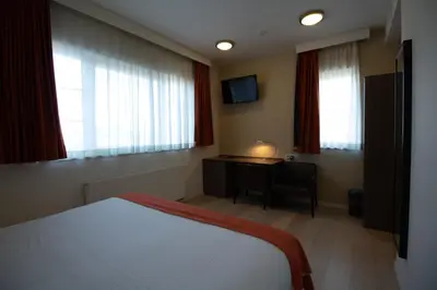 a bedroom with a bed and a desk and windows at Hotel Taormina Brussels Airport in Zaventem
