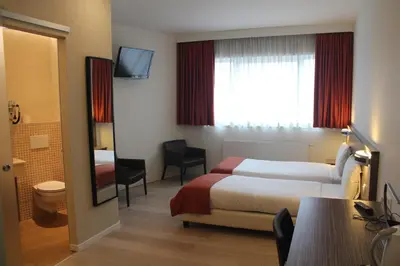 a hotel room with a bed and a bathroom at Hotel Taormina Brussels Airport in Zaventem