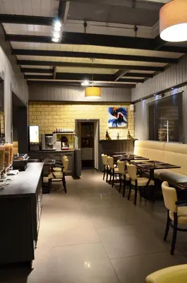 a dining room with tables and chairs and a kitchen at Hotel Taormina Brussels Airport in Zaventem