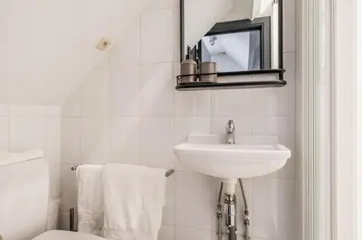 a white bathroom with a sink and a mirror at Simone's Kitchen B&B in Antwerp