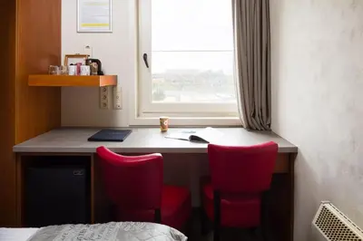 a room with a desk with red chairs and a window at Vivaldi Hotel in Westerlo