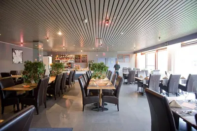 a dining room with tables and chairs and a man in the background at Vivaldi Hotel in Westerlo